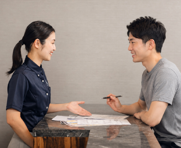 スポーツクラブの施設についてご案内をする女性スタッフと利用する男性